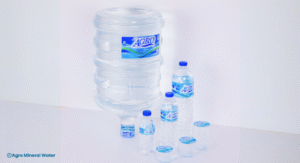Berbagai kemasan produk Agro Mineral Water mulai dari gelas plastik kecil, botol ukuran sedang, hingga galon besar, ditata rapi di atas permukaan putih dengan latar belakang bersih, menampilkan variasi produk air mineral berkualitas untuk memenuhi kebutuhan hidrasi konsumen.
